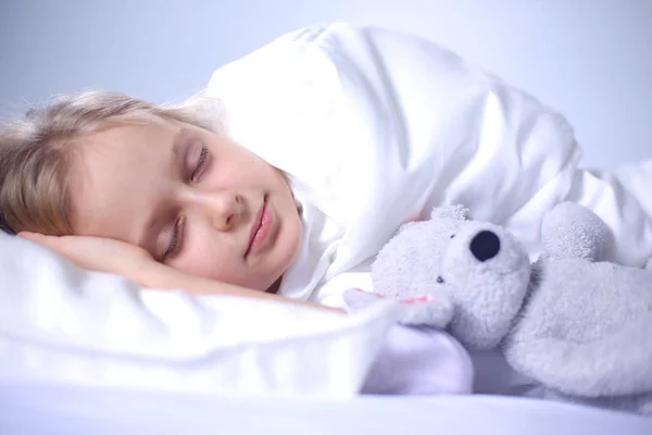 Bambino bambina dorme nel letto con un orsacchiotto giocattolo . — Foto Stock