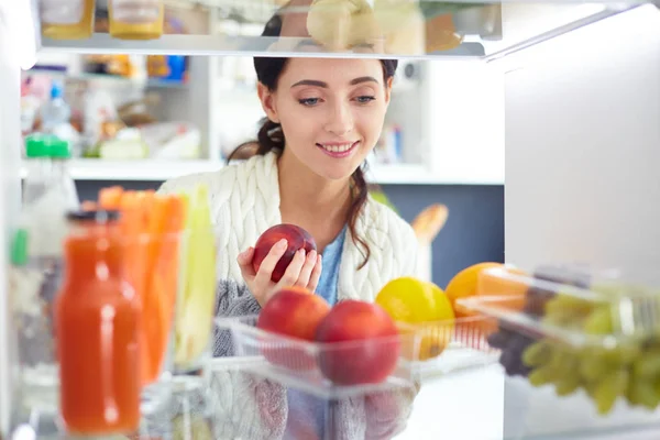 Retrato de fêmea em pé perto da geladeira aberta cheia de alimentos saudáveis, legumes e frutas. Retrato de fêmea — Fotografia de Stock