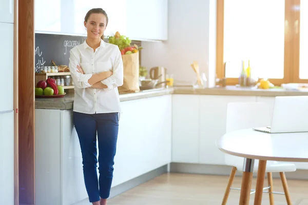 Портрет молодой женщины, стоящей со скрещенными руками на кухонном фоне. Женщина на кухне . — стоковое фото
