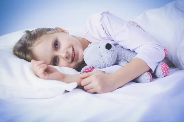 Kleines Mädchen schläft im Bett mit einem Spielzeug-Teddybär. — Stockfoto