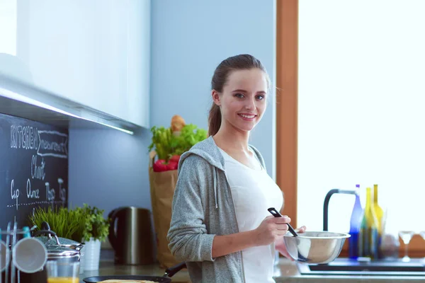 Mujer joven prepara panqueques en la cocina mientras está de pie cerca de la mesa. Mujer en la cocina. Cocinar en la cocina. —  Fotos de Stock