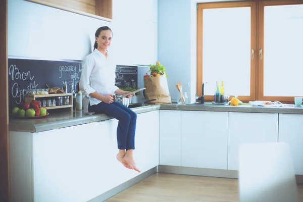 Retrato de mujer joven de pie sobre el fondo de la cocina . — Foto de Stock