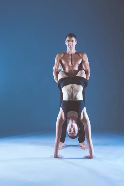 Young couple practicing acro yoga on mat in studio together. Acroyoga. Couple yoga. Partner yoga. Stock Photo