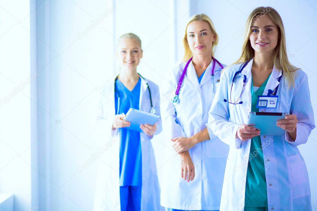 Portrait of three confident female doctors standing with arms crossed at the medical office.