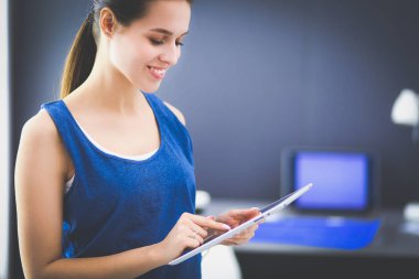 Ev ofisinde tablet üzerinde çalışan çekici bir kadın.