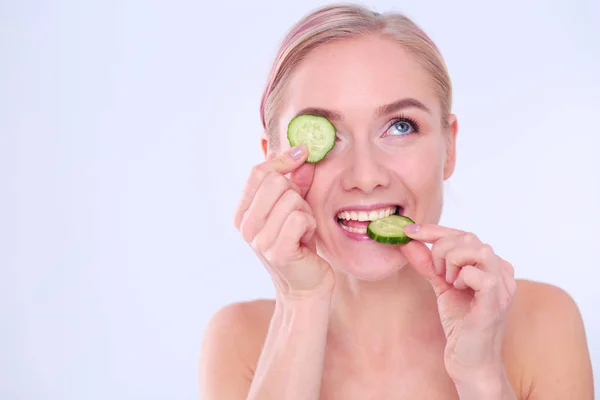 Mooie jongedame met plakjes komkommer op witte achtergrond. — Stockfoto