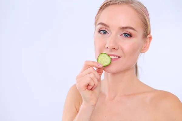Mooie jongedame met plakjes komkommer op witte achtergrond. — Stockfoto