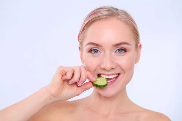 Mooie jongedame met plakjes komkommer op witte achtergrond. — Stockfoto