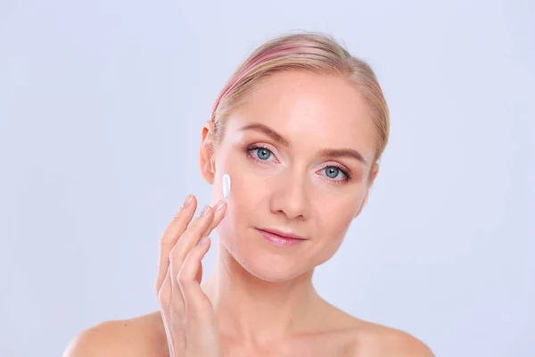 La belle jeune fille avec une peau propre et fraîche touche avec une main une joue — Photo