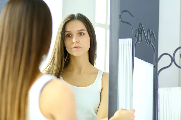 Junge Frau spiegelt sich zu Hause im Spiegel — Stockfoto