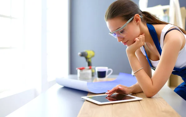 Ung kvinna stående nära skrivbord och tittar på blåkopian för nya hem — Stockfoto