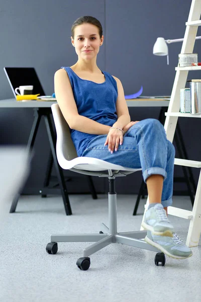 Giovane donna seduta sulla scrivania in ufficio — Foto Stock