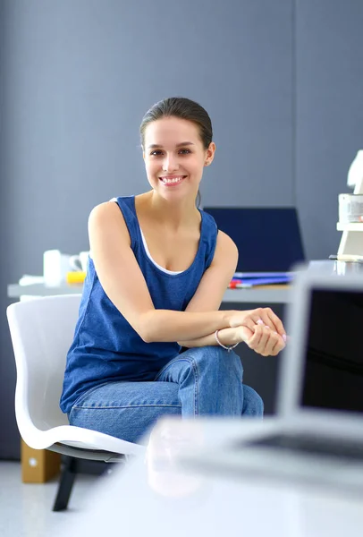 Giovane donna seduta sulla scrivania in ufficio — Foto Stock