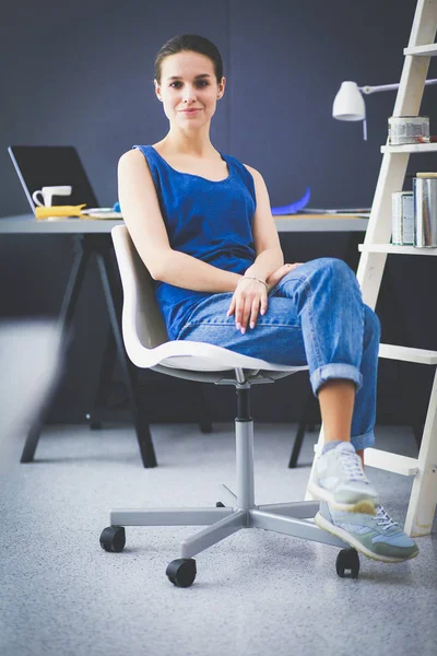 Giovane donna seduta sulla scrivania in ufficio — Foto Stock