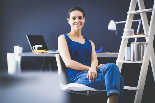 Young woman sitting on the desk in office — Stock Photo, Image