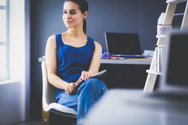 Giovane donna seduta sulla scrivania in ufficio — Foto Stock