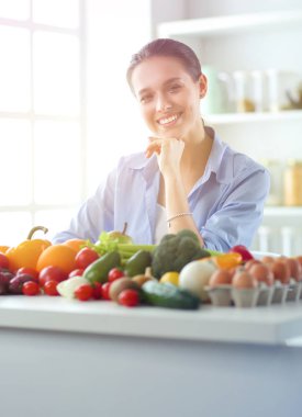 Ahşap iç kısımda meyve ve sebze dolu masada oturan genç ve tatlı bir kadın.