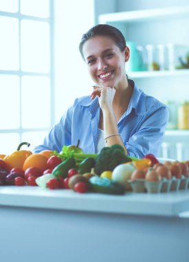Ahşap iç kısımda meyve ve sebze dolu masada oturan genç ve tatlı bir kadın.