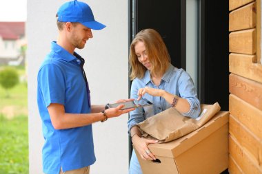 Mavi üniformalı gülümseyen kurye servis konseptine paket kutusu teslim eden teslimatçı. Mavi üniformalı gülümseyen teslimatçı.