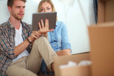 Genç bir çift yeni ev içinde hareket. Oturma ve açma sonra rahatlatıcı. Bir şey üstünde laptop arıyorum. Genç Çift