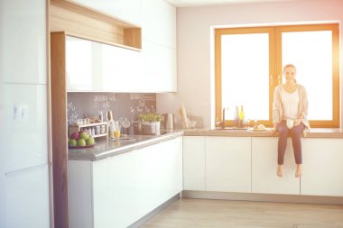 Mutfakta dijital tablet kullanan güzel genç bir kadın..