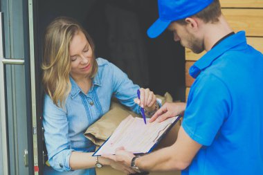 Mavi üniformalı gülümseyen kurye servis konseptine paket kutusu teslim eden teslimatçı. Mavi üniformalı gülümseyen teslimatçı.