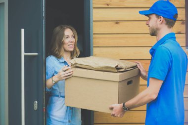 Mavi üniformalı gülümseyen kurye servis konseptine paket kutusu teslim eden teslimatçı. Mavi üniformalı gülümseyen teslimatçı.