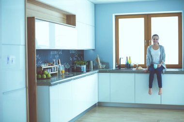 Mutfakta dijital tablet kullanan güzel genç bir kadın..