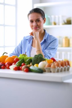 Ahşap iç kısımda meyve ve sebze dolu masada oturan genç ve tatlı bir kadın.
