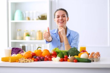 Ahşap iç kısımda meyve ve sebze dolu masada oturan genç ve tatlı bir kadın.