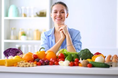 Ahşap iç kısımda meyve ve sebze dolu masada oturan genç ve tatlı bir kadın.