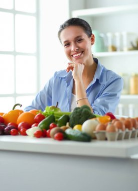 Ahşap iç kısımda meyve ve sebze dolu masada oturan genç ve tatlı bir kadın.