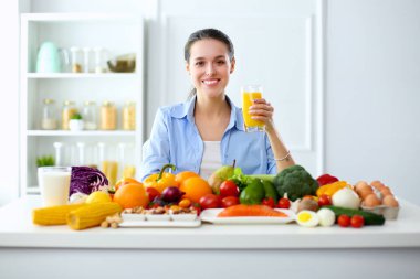 Ahşap iç kısımda meyve ve sebze dolu masada oturan genç ve tatlı bir kadın.