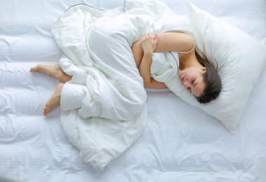 Güzel bir kadın yatağında uzanıyor.