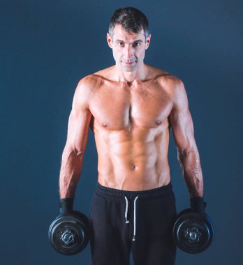 Yakışıklı kaslı adam dumbell ile çalışma dışarı. Kişisel fitness eğitmeni. Kişisel eğitim.