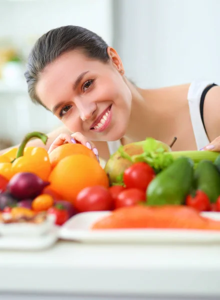 젊고 귀여운 여자 목조 인테리어에 야채와 과일의 전체 테이블에 앉아 — 스톡 사진