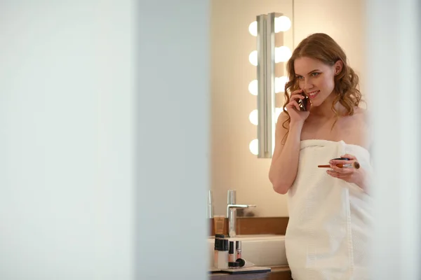 Ung kvinna stående på badrum med telefon. — Stockfoto