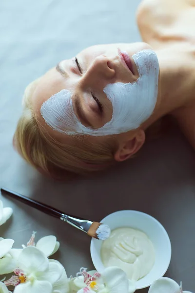 Mascarilla facial. Hermosa joven en el spa, mujer cosmética aplicando mascarilla facial . — Foto de Stock