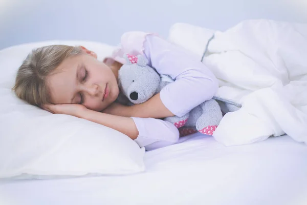 Çocuk oyuncak oyuncak ayı ile yatakta uyur küçük kız. — Stok fotoğraf