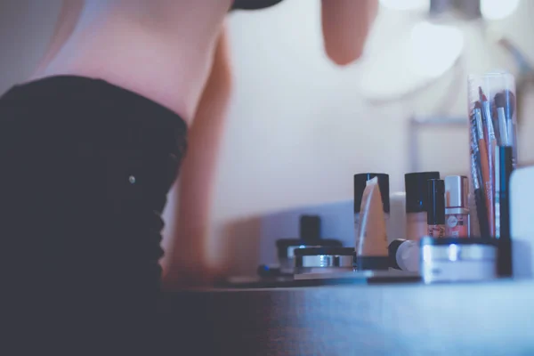 Mujer joven mirándose en el espejo en el baño . — Foto de Stock