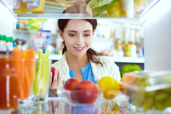 Portrait of female standing near open fridge full of healthy food, vegetables and fruits. Portrait of female — Stock Photo, Image