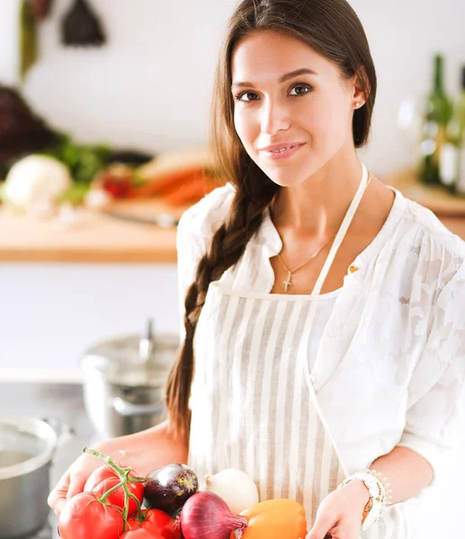 Lachende jonge vrouw met groenten in de keuken. Glimlachende jonge vrouw — Stockfoto