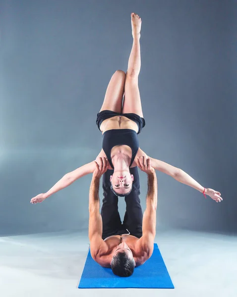 Giovane coppia praticare acro yoga sul tappeto in studio insieme. Acroyoga. Un paio di yoga. Partner yoga . — Foto Stock