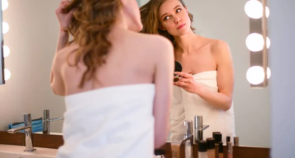 Fiatal nő néz a tükörbe, és smink fel. — Stock Fotó