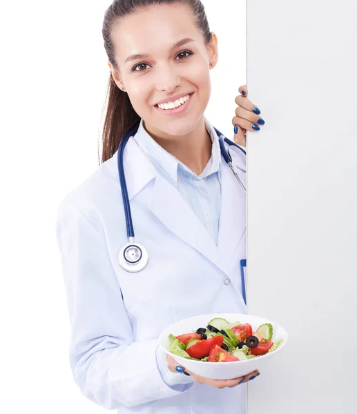 Retrato de una hermosa doctora sosteniendo un plato con verduras frescas en blanco. Mujeres doctores — Foto de Stock