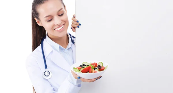 Retrato de uma mulher bonita médico segurando um prato com legumes frescos em pé perto de branco. Mulheres médicas — Fotografia de Stock