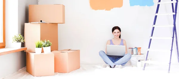 Junge Frau beim Bemalen der neuen Wohnung, sitzend mit Laptop. junge Frau mit Laptop — Stockfoto