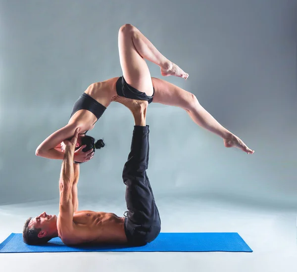 Pareja joven practicando acro yoga en estera en estudio juntos. Acroyoga. Un par de yoga. Socio yoga . — Foto de Stock