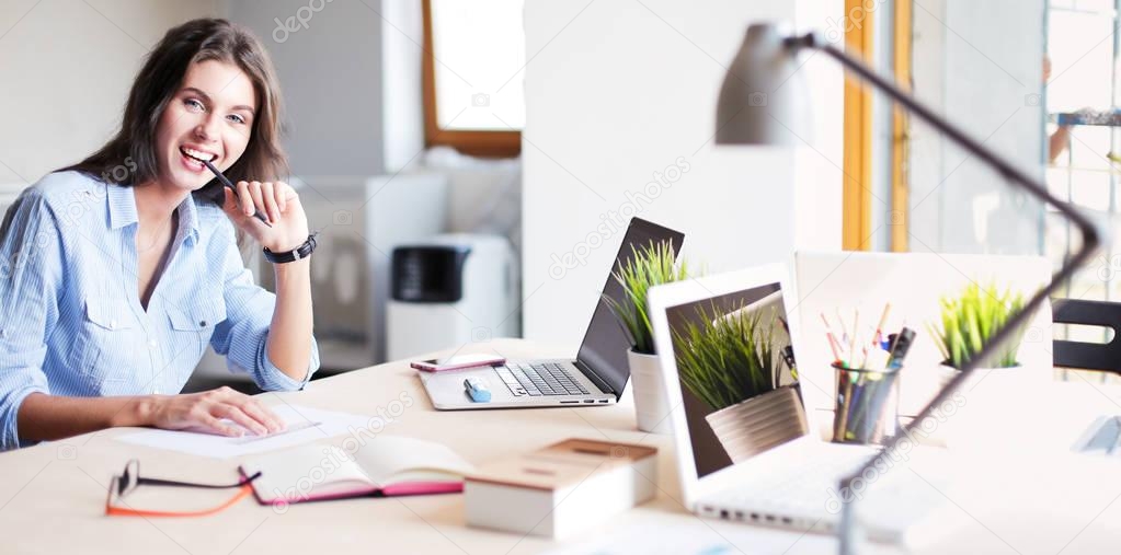 Young woman sitting at office table with laptop. Young woman. Laptop