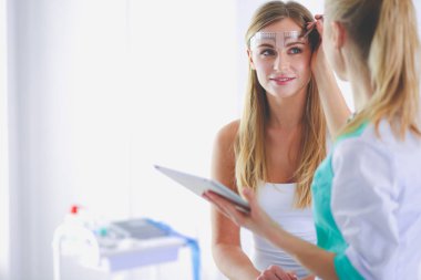 Kaşlar için kalıcı makyaj. Güzellik salonunda kalın kaşlı güzel bir kadın..